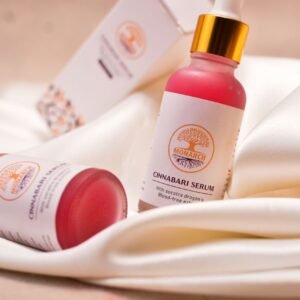 Elegant close-up of Cinnabari serum bottles on white fabric, showcasing luxury skincare packaging.